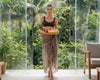 Woman holding a tray of fruits in a tropical setting