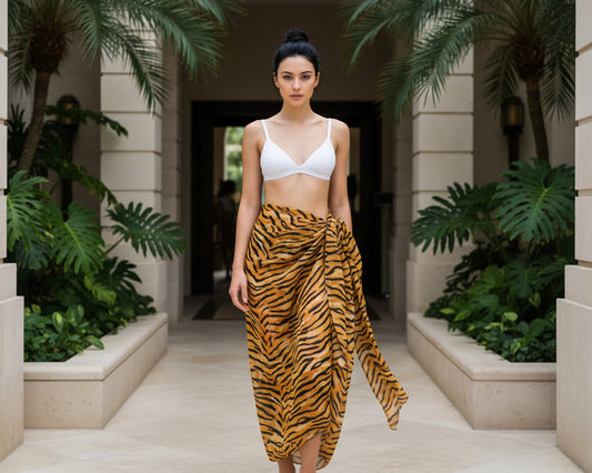Woman in a white sarong top and tiger striped sarong standing in a tropical setting with plants and stone architecture.