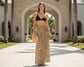 Woman in black bikini top and leopard print skirt standing in front of a building with palm trees.