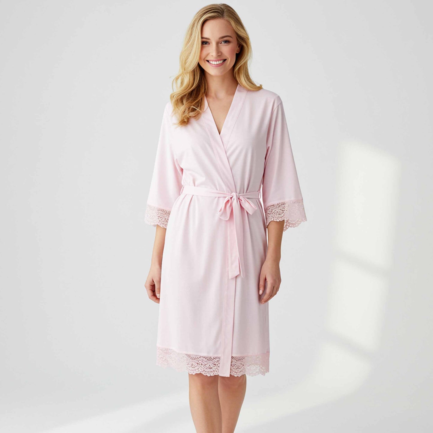Woman wearing a pink robe with lace details on a white background