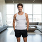 Man in a white tank top and black shorts standing in a modern living room.